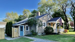 Ett tvåvåningshus med en veranda på framsidan, ett garage och en liten trädgård.