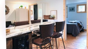 Habitación compacta con comedor, cama y pequeña kitchenette.