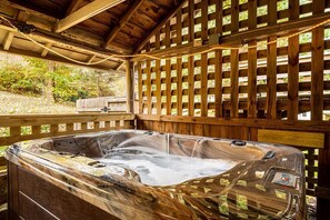 Un jacuzzi bajo una pérgola de madera, con una valla de madera al fondo.
