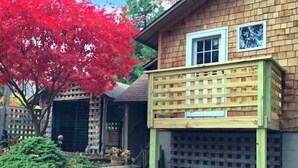 Una casa de dos pisos con fachada de madera, un garaje y un porche cubierto.