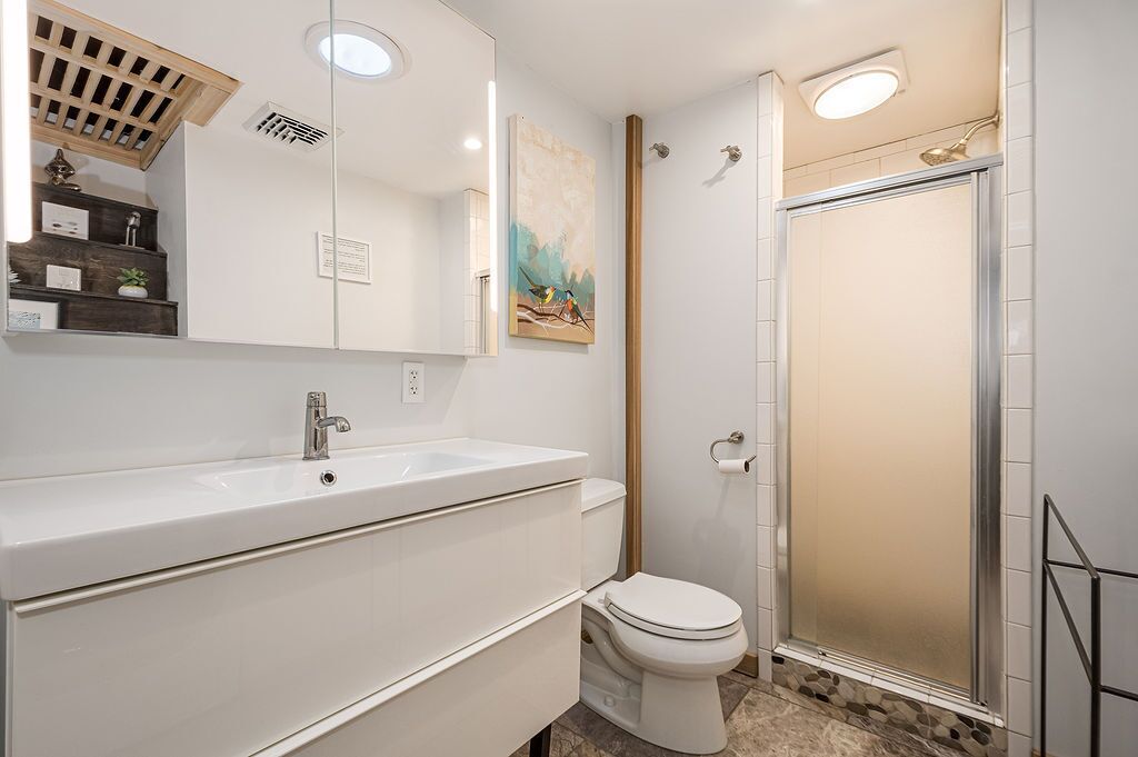 Une salle de bain moderne avec un meuble-lavabo blanc, des toilettes et une douche à parois de verre.