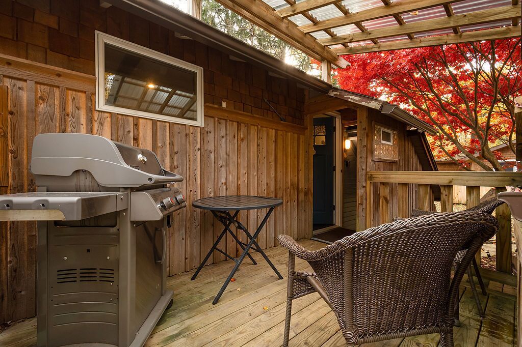 A wooden deck with a grill, a table, and a wicker chair.