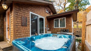 A wooden cabin with a hot tub filled with ice, a dining table, and a laptop on the deck. - Cozy Cottage - Perfect Private Getaway. (Hopwood)