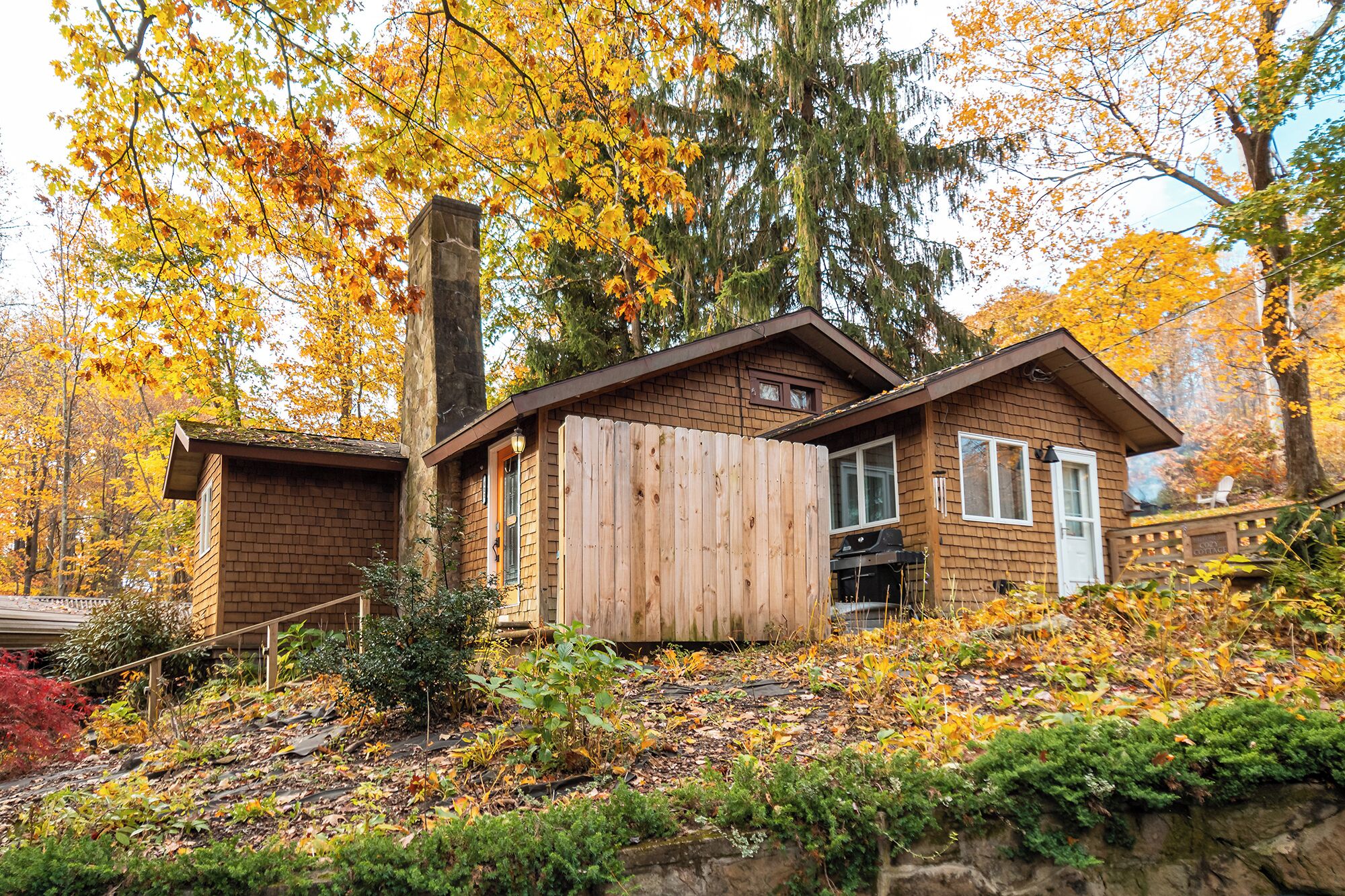 A cabin with a brick exterior, a wooden deck, and a chimney.