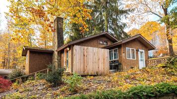 A cabin with a brick exterior, a wooden deck, and a chimney.