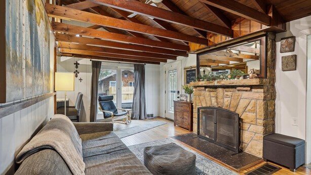 A cozy living room with a stone fireplace, wooden beams, a sofa, and a chair. - Cozy Cottage - Perfect Private Getaway. (Hopwood)