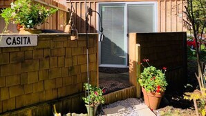 Una casa de ladrillo con un letrero que dice "CASITA", una puerta principal y plantas en macetas.