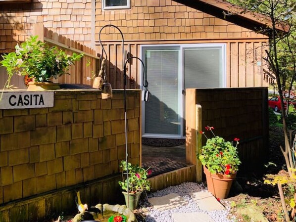A brick house with a sign reading "CASITA," a front door, and potted plants.