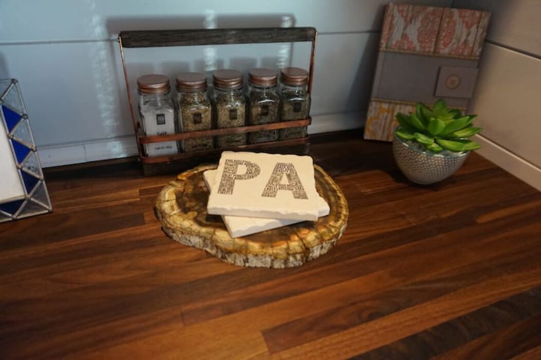A wooden floor with a rustic centerpiece featuring jars and a letter 'PA' on a wooden coaster.