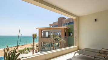 Een balkon met uitzicht op zee, een potplant en een bed.