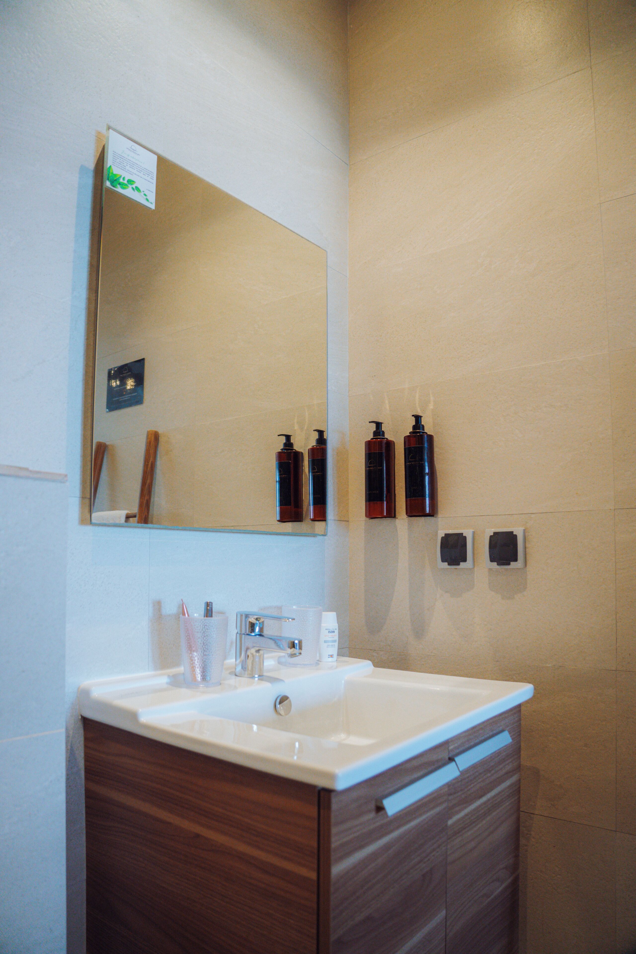 A bathroom with a sink, mirror, and toiletries.