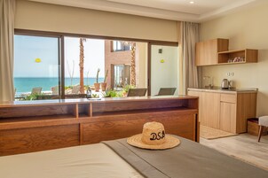 Habitación de hotel con vista al mar, un escritorio de madera, un sombrero y una kitchenette.