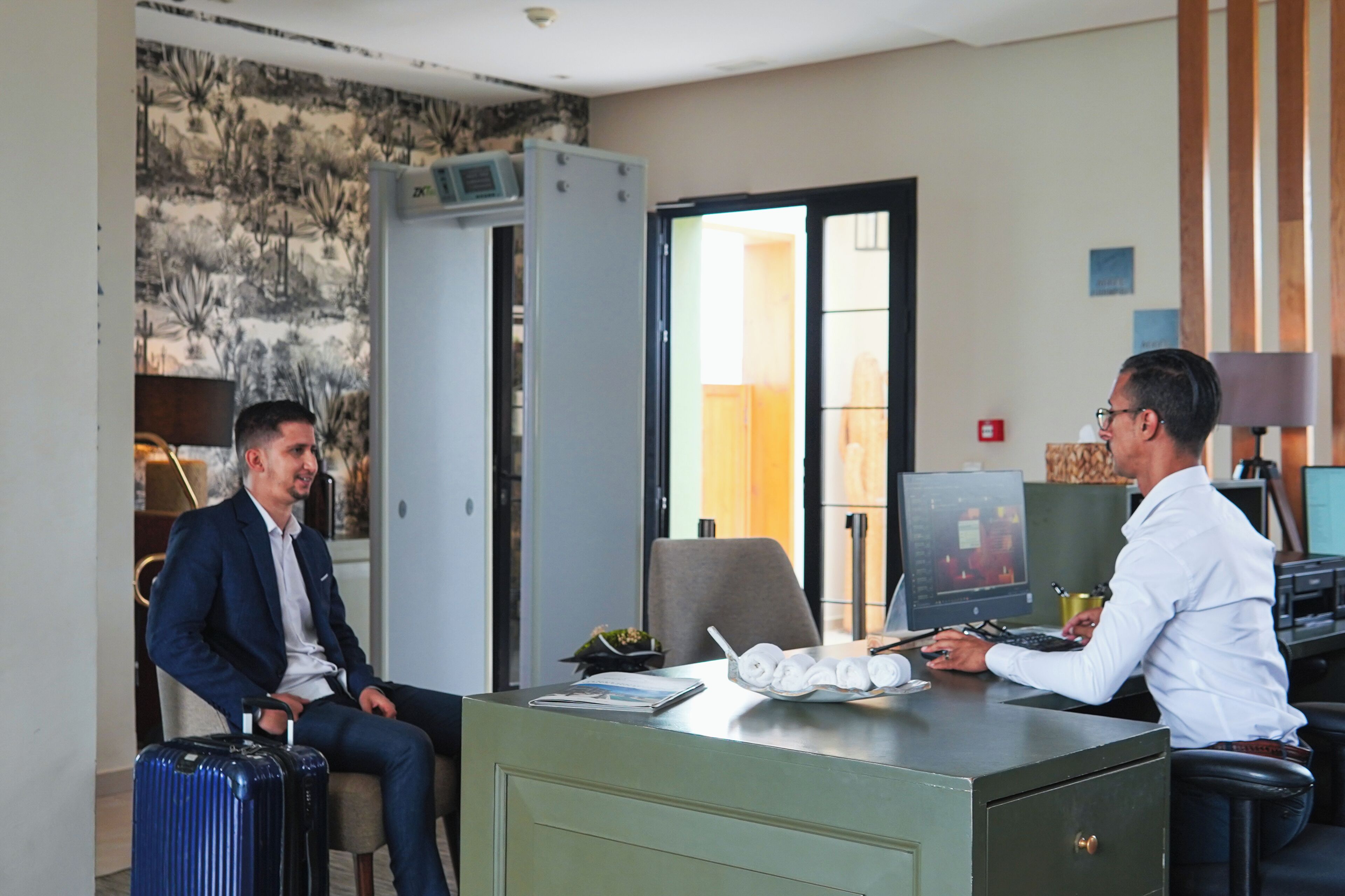 Une chambre d’hôtel équipée d’un bureau, d’un ordinateur, d’une chaise et d’une valise.