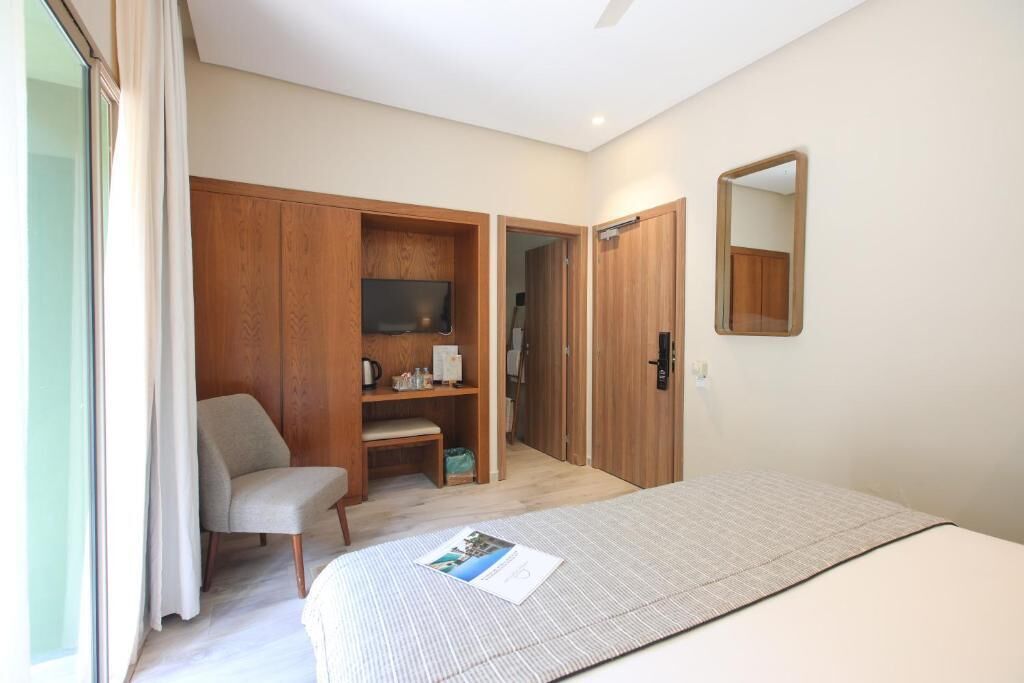 A bedroom with a bed, a chair, a wardrobe, and a mirror.