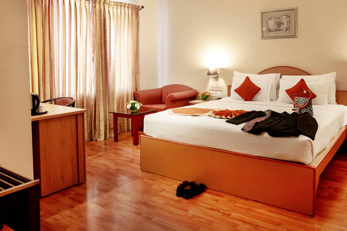 Ein Hotelzimmer mit einem großen Bett, einem Schreibtisch, einem Stuhl, einem Nachttisch und einer Lampe.