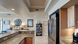 A modern kitchen with granite countertops, stainless steel appliances, and wooden cabinetry. - Dunes of Crystal Beach 104 | Free Seasonal Beach Service & More! (Destin)