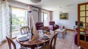 Un comedor con una mesa redonda para cuatro personas, un sofá, un televisor y un cuadro en la pared.