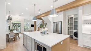 A modern kitchen with a large island, built-in appliances, and pendant lighting.