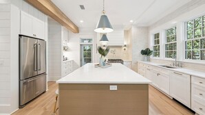 A modern kitchen with a large island, stainless steel appliances, and a hanging pendant light.