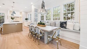 A spacious kitchen with a central island, pendant lighting, and a seating area with a sofa and cushions.
