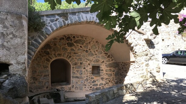 A stone building with an arched doorway and a small window. - Maison de Village Avec vue Imprenable sur le Cap Corse (Santa-Reparata-Di-Balagna)