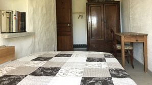 A bedroom with a bed, a wooden desk, a wardrobe, and a shelf with books. - Maison de Village Avec vue Imprenable sur le Cap Corse (Santa-Reparata-Di-Balagna)