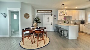 A modern kitchen with white cabinetry, a central island with bar stools, and a hanging light fixture.