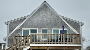 A two-story house with a wooden deck, a balcony, and a triangular roof.