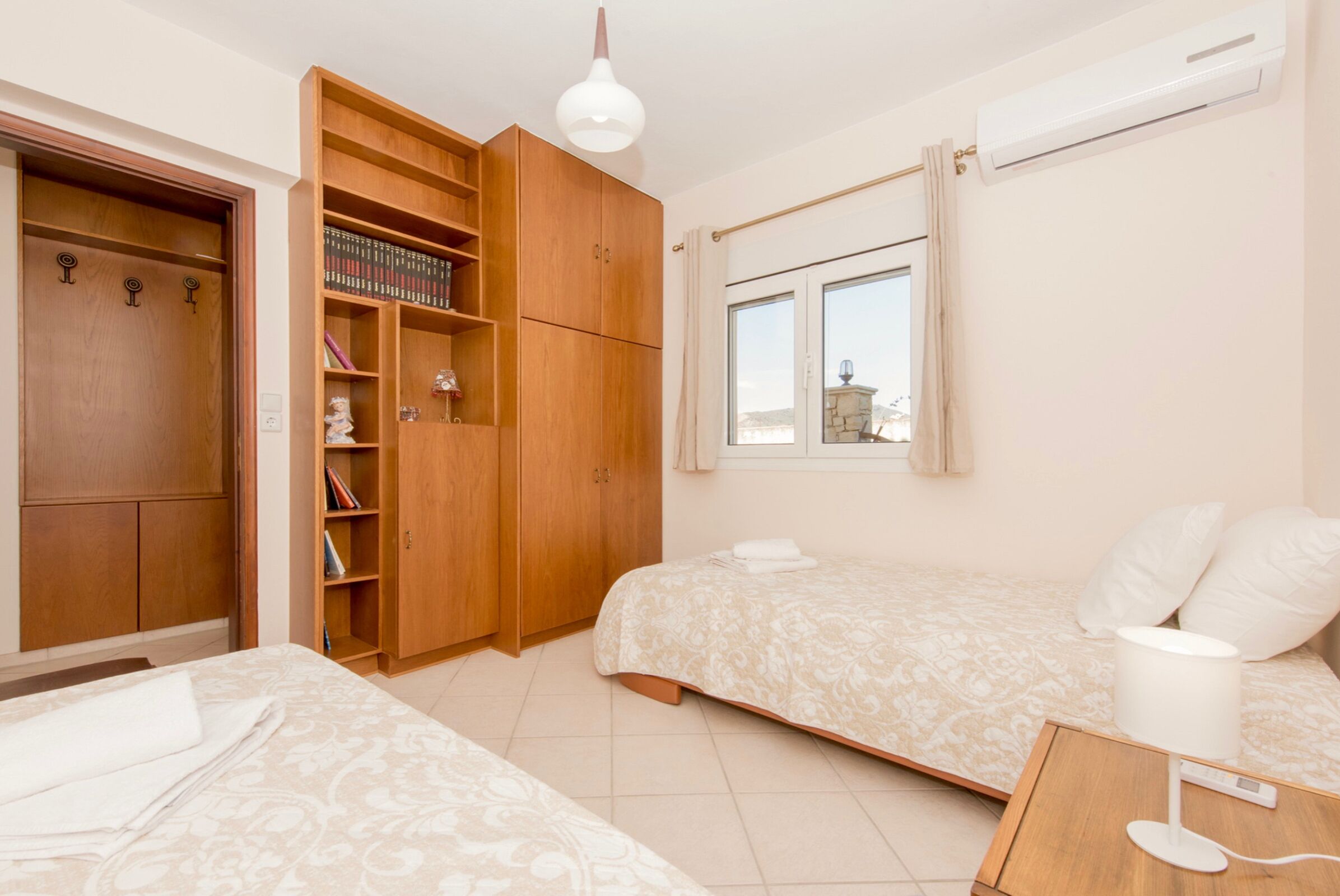 Ein Schlafzimmer mit zwei Betten, einem Kleiderschrank und einem Bücherregal.