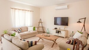A living room with a sofa set, a coffee table, a TV, and a lamp. - Villa Korini Crete (Mylopotamos)