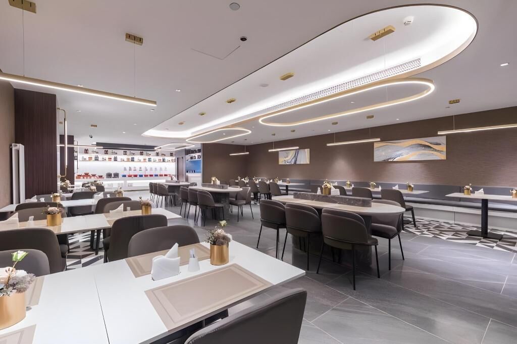 Een modern restaurant met een strak, eigentijds design, een centrale bar, meerdere eettafels en een vloer met een patroon.