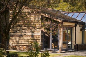 A wooden cabin with a stone foundation, large glass doors, and a sloped roof.