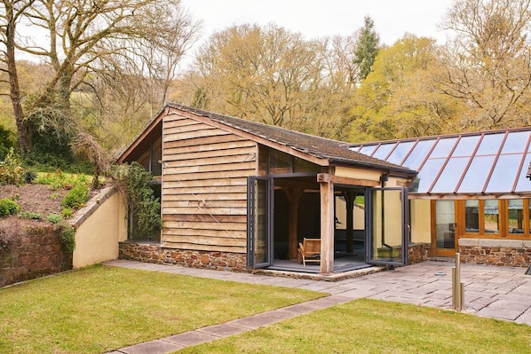A wooden cabin with a glass extension, stone walls, and a stone pathway.