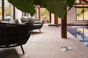 A modern indoor pool area with wicker furniture and a view of the outdoors. - Swifts Return (Lower Ashton)