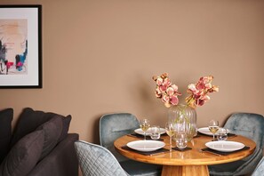 A dining table set with plates, glasses, and a vase of flowers. - The Moorings (Torquay)