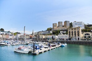A marina with multiple boats docked, surrounded by buildings with varied architecture.