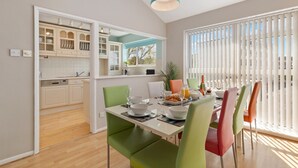 Een moderne keuken met witte kasten en een eetgedeelte met kleurrijke stoelen.