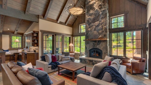 A spacious living room with a stone fireplace, large windows, and a high ceiling. - Fresh Tracks at Northstar- TLUXP (Truckee)