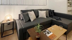 Un salon moderne avec un canapé d’angle, une table basse en bois et une table d’appoint avec une lampe.