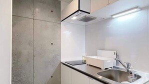 Une cuisine moderne avec des meubles blancs, un évier en acier inoxydable et un four encastré.