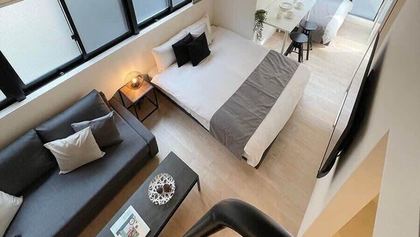 Una habitación de hotel moderna con una cama, un sofá, una mesita y un ventanal.