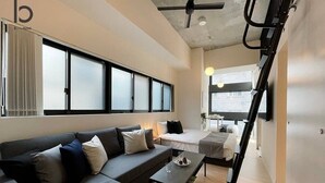 Una habitación de hotel moderna con sofá, una mesita, cama y una escalera.