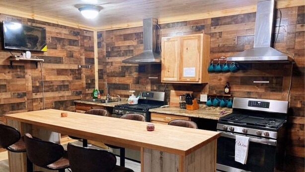Une cuisine avec des murs en bois, une table à manger en bois et un poêle.