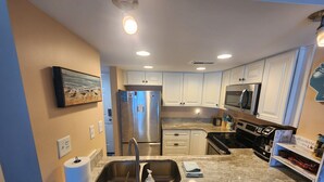 A modern kitchen with stainless steel appliances, white cabinetry, and a granite countertop. - HERE YA' GO! ST REGIS UNIT 1310 OCEANFRONT! YOUR HAPPY PLACE! 2 BR 2 BA CONDO! (North Topsail Beach)
