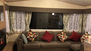 A cozy living room with a sectional sofa, a flat-screen TV, and a wooden cabinet.