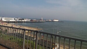 Een kustgezicht met een promenade, een steiger en gebouwen op de achtergrond.