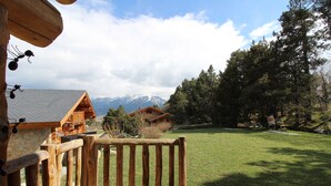Een houten terras met uitzicht op een bergketen en een houten chalet.