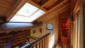 Een houten interieur met een dakraam, houten balken en een trap.