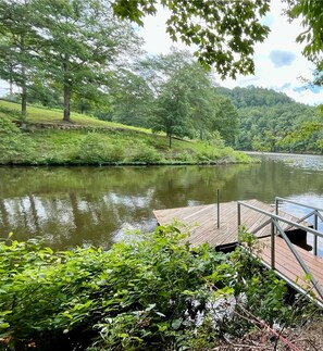 Guests can enjoy serene lakeside views from the dock, surrounded by lush greenery and tranquil atmosphere.