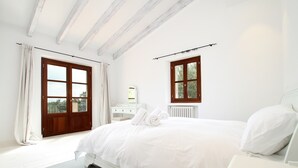 Ein Schlafzimmer mit einem großen Bett, einem Schreibtisch und zwei Fenstern.
